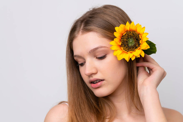 Teenager Russian girl isolated on white background holding a sunflower. Close up portrait - Photo, image