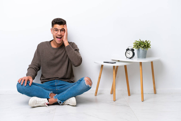 Young caucasian man sitting in his home isolated on white background with surprise and shocked facial expression - Photo, Image