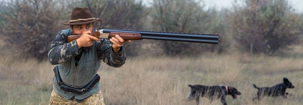 Homme chasseur en camouflage avec une arme à feu pendant la chasse à la recherche d'oiseaux sauvages ou de gibier. - Photo, image