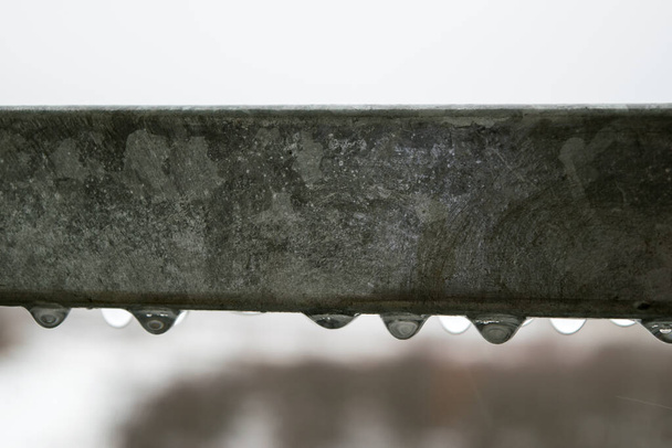 Προβολή των σταγονιδίων νερού που κρέμονται από ένα μεταλλικό κιγκλίδωμα σε μια βροχερή μέρα - Φωτογραφία, εικόνα