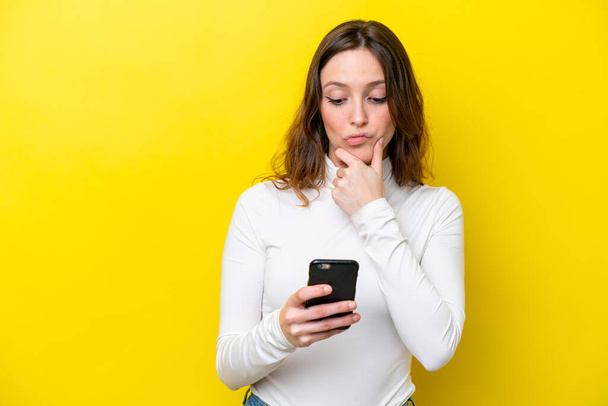 Young caucasian woman isolated on yellow background thinking and sending a message - Foto, immagini