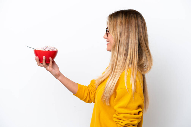 Young Uruguayan woman holding a bowl of cereals isolated on white background with happy expression - Foto, immagini