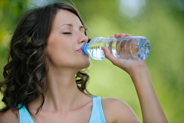 молода темноволоса жінка п'є воду
 - Фото, зображення