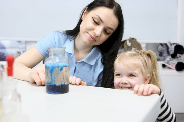 Küçük bilim adamı. Meraklı kız anne ile oynuyor eğitim aktivitesi komik bir deney yapıyor. İlgilenen küçük kız, ablasını kimyasal test yaparken izliyor. Kimya seti kullanıyor. - Fotoğraf, Görsel