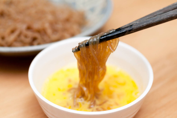 Sweet and spicy boiled Konjac noodles is dipped into a raw egg. - Foto, immagini