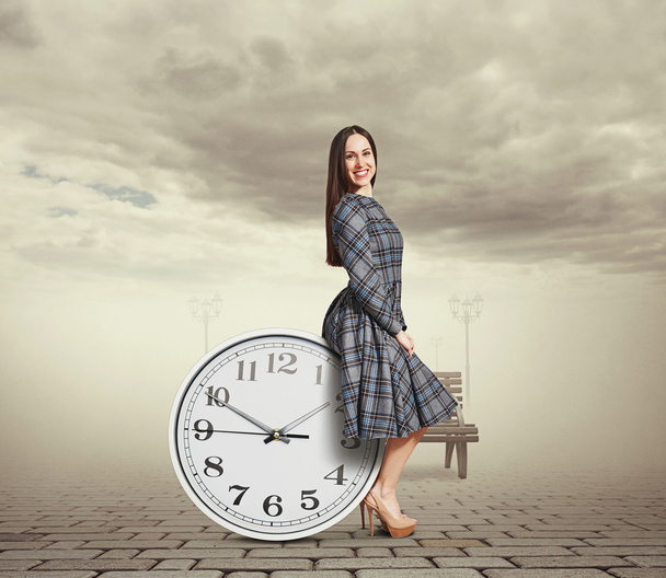 beautiful young woman sitting on the clock - Zdjęcie, obraz