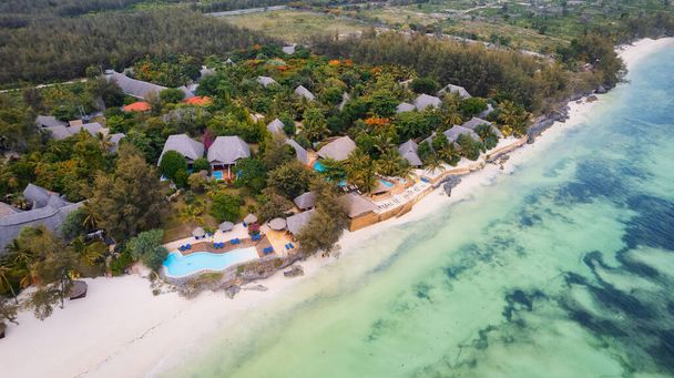 Indulge in a luxurious getaway at Zanzibar's Kiwengwa beach, where the white sand, turquoise waters, and palm trees create a serene and refreshing atmosphere for a truly memorable vacation. - Foto, Imagem
