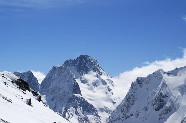Inverno montagne innevate tra nuvole e bel cielo blu nella giornata di sole. Caucaso Montagne, regione Dombay. - Foto, immagini