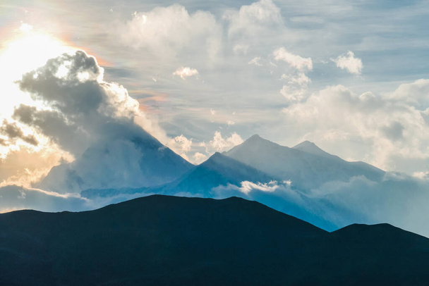 Güneş ışığı Himalaya Tepeleri, Annapurna Circuit Trek, Nepal üzerindeki bulutları yendi. Sis kaplı yamaçlar. Keskin yamaçlar. Önünde gölgelerle kaplı daha küçük bir dağ. Bulutlu ama güneşli. - Fotoğraf, Görsel