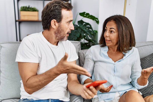 Hombre y mujer de mediana edad pareja con problemas de infidelidad utilizando el teléfono inteligente en casa - Foto, Imagen