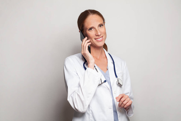 Successful attractive mid adult woman doctor medical worker holding smartphone in her hand, modern female portrait - Foto, immagini