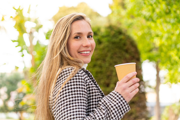 Young blonde woman holding a take away coffee at outdoors - Photo, image