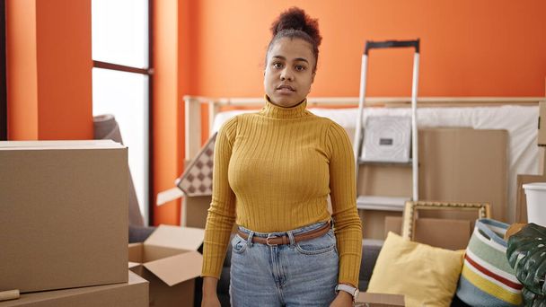 Young african american woman standing looking serious at new home - Foto, Imagem