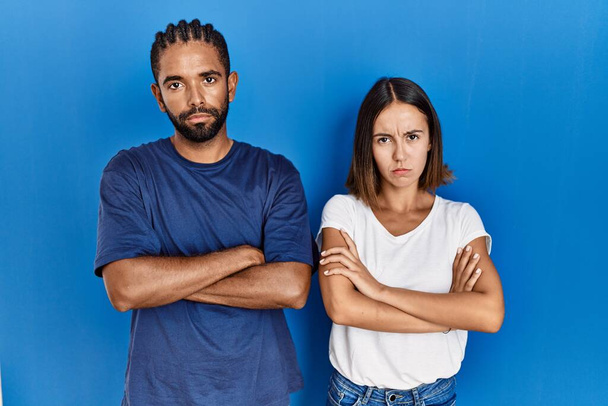 Young hispanic couple standing together skeptic and nervous, disapproving expression on face with crossed arms. negative person.  - Foto, Imagem