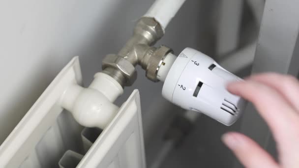 Woman turns off the heating by setting the thermostat of the central heating radiator to the minimum mode of maintaining the temperature in the room, number zero, saving money energy and gas crisis - Materiał filmowy, wideo
