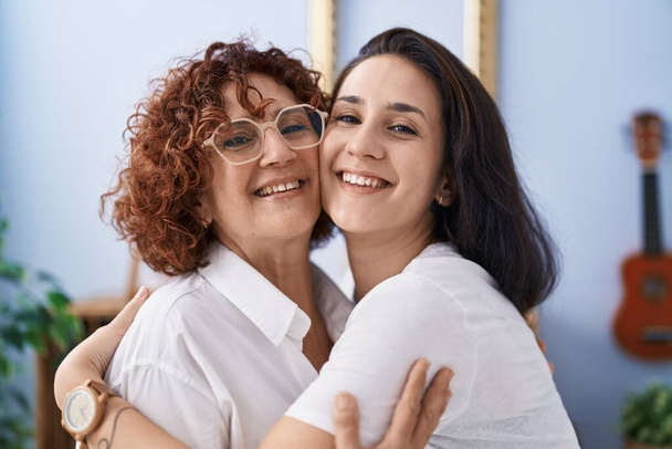 Zwei Frauen Mutter und Tochter umarmen einander zu Hause stehend - Foto, Bild