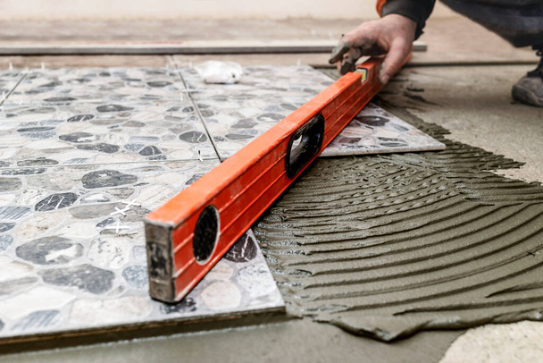 Deitado telha cerâmica no piso de concreto por Tiler com nível e argamassa. Home Renovação e Construção de novo conceito de casa. - Foto, Imagem