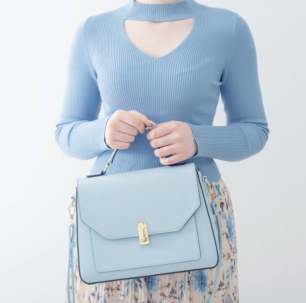 young girl in blue blouse  and pleated skirt with blue handbag on white background - Photo, Image