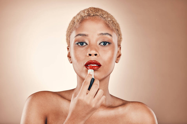 Black woman, makeup and portrait with red lipstick on a brown background for beauty cosmetics. Aesthetic model or focus person in studio for skincare, self care and facial glow on skin and bold lips. - Valokuva, kuva