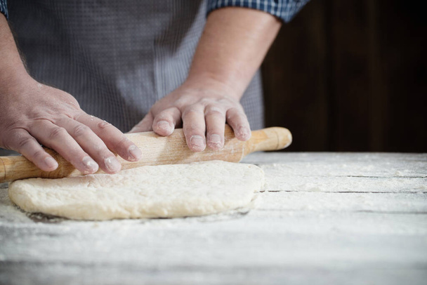 hands cooking dough on dark wooden background - Foto, Bild