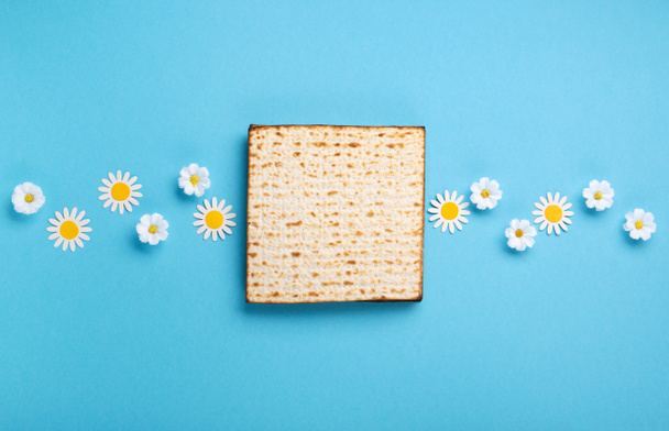 Joodse feestdag Pascha wenskaart concept met matza, noten, lente bloemen op blauwe tafel. Seder Pesach voorjaarsvakantie achtergrond, bovenaanzicht, kopieerruimte. - Foto, afbeelding