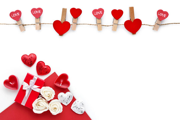 Clothespins with red hearts on rope and red gift box with roses isolated on white background. Top view. Greeting card. Space for your text - 写真・画像