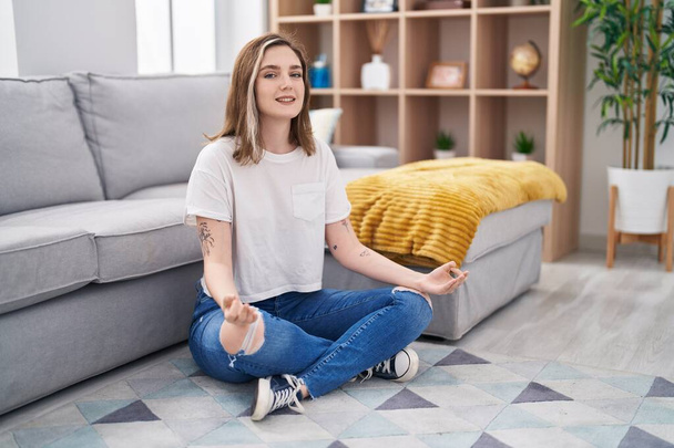 Fiatal nő jóga gyakorlat ül a padlón otthon - Fotó, kép