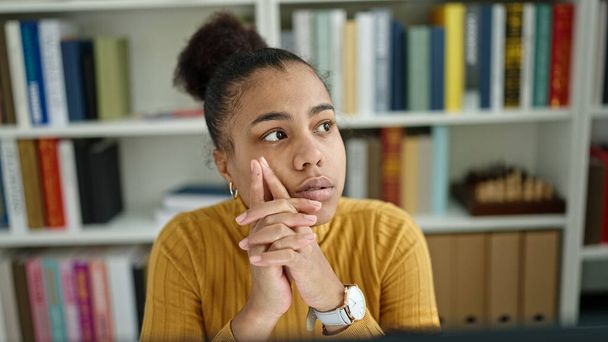 Nuori afrikkalainen amerikkalainen nainen opiskelija tietokoneella ajattelu kirjastossa - Valokuva, kuva