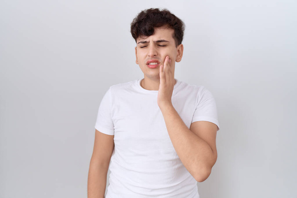 Young non binary man wearing casual white t shirt touching mouth with hand with painful expression because of toothache or dental illness on teeth. dentist  - Foto, Imagem