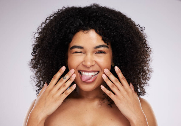 Black woman, tongue and afro in studio portrait with beauty, wellness and cosmetic skincare glow by background. Young gen z model, african and cosmetics with funny face, natural and healthy aesthetic. - Foto, Imagem