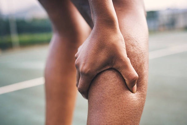 Knee injury, fitness pain and netball athlete on a outdoor sports court with joint or muscle problem. Training, exercise and black woman hands holding legs with muscle and wellness issue from game. - Fotoğraf, Görsel