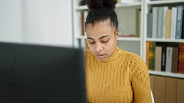 Νεαρή Αφρο-Αμερικανίδα φοιτήτρια που χρησιμοποιεί υπολογιστή για σπουδές στη βιβλιοθήκη - Φωτογραφία, εικόνα