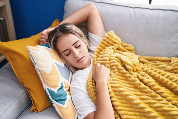 Joven mujer rubia tumbada en el sofá durmiendo en casa - Foto, Imagen