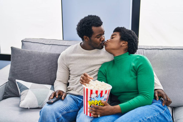 Африканський американець і жінка дивляться, як кіно поїдає попкорн вдома. - Фото, зображення