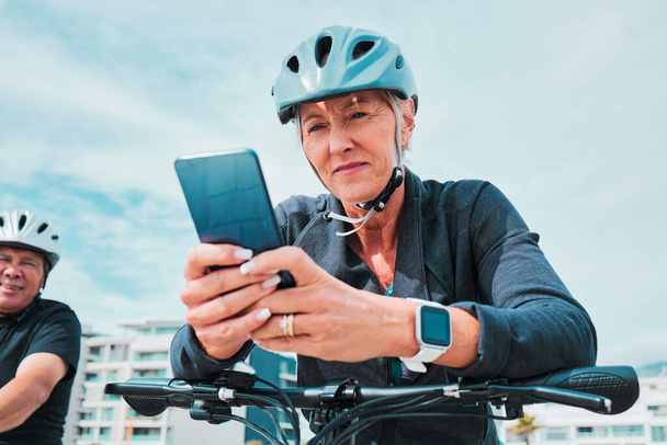 Mature woman, phone or electrical bike helmet in transport location, clean energy or sustainability travel with GPS map. Technology, electric or eco friendly bicycle and mobile, cycling man or couple. - Photo, Image