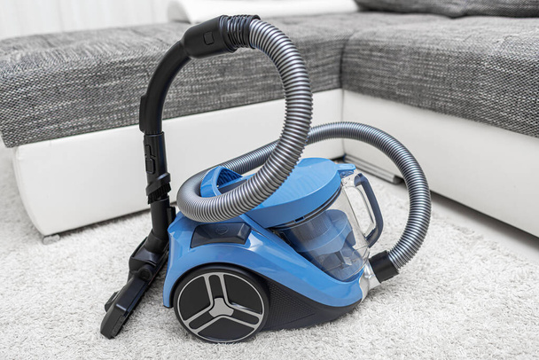 Modern vacuum cleaner in the living room. Vacuum cleaner on the background of the home interior. - Fotó, kép