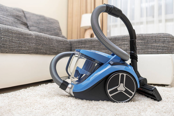 Modern vacuum cleaner in the living room. Vacuum cleaner on the background of the home interior. - Zdjęcie, obraz