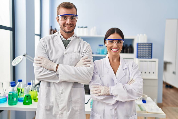 Man and woman scientist partners standing with arms crossed gesture at laboratory - Photo, Image