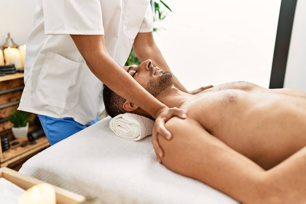 Двоє іспаномовних чоловіків терапевт і пацієнт мають масаж обличчя в центрі краси
 - Фото, зображення