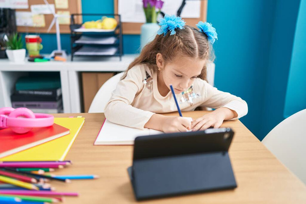 Schattige blanke meisje student met behulp van touchpad schrijven op notebook op kantoor - Foto, afbeelding