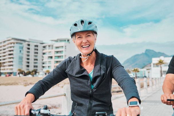 Ώριμη γυναίκα, ποδήλατο ή κράνος πορτρέτο για παραλιακό περίπατο ποδηλασία σε άσκηση ευεξίας, γυμναστήριο ή καρδιολογία υγειονομικής περίθαλψης. Χαμόγελο, χαρούμενος ή ηλικιωμένος σε ποδήλατο κεφάλι ασφάλεια ή φιλικό προς το περιβάλλον προπόνηση. - Φωτογραφία, εικόνα