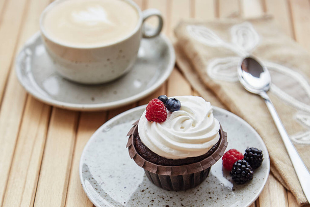 French dessert - cupcake with berries and cup of cappucino. Cozy breakfast at the terrace. Dreamy Escapism concept. - Foto, imagen