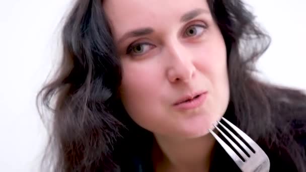 on white background woman in black clothes eats a salad and meat with fork looks into the frame space for text proper nutrition white background one woman tasteless food forced diet - Filmagem, Vídeo