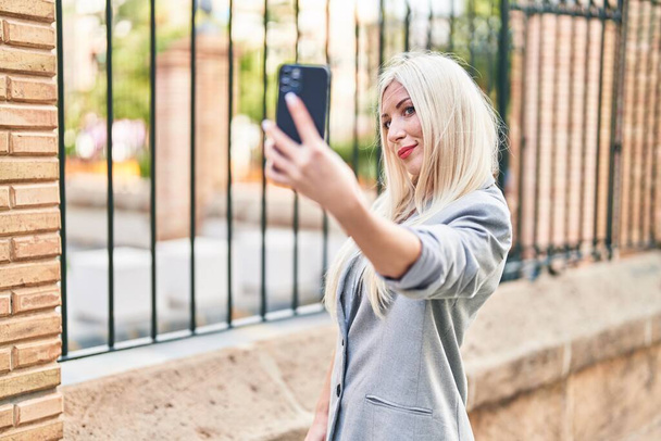 Young blonde woman smiling confident making selfie by the smartphone at street - Foto, Imagem