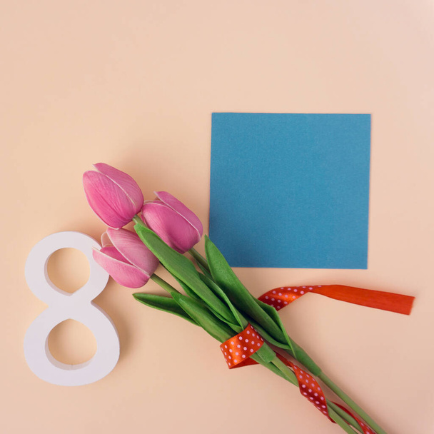 8 de marzo, Día Internacional de la Mujer, tulipanes, flores de tulipán y papel blanco sobre fondo rosa - Foto, imagen