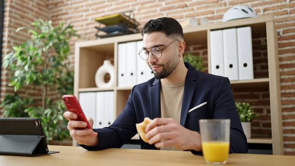 Jovem árabe homem empresário tomando café da manhã trabalhando no escritório - Foto, Imagem