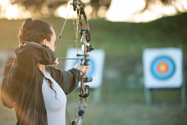 Sports archer, target and bow and arrow training for archery competition, athlete challenge or girl field practice. Shooting, objective and competitive woman focus on precision, aim or mock up. - 写真・画像