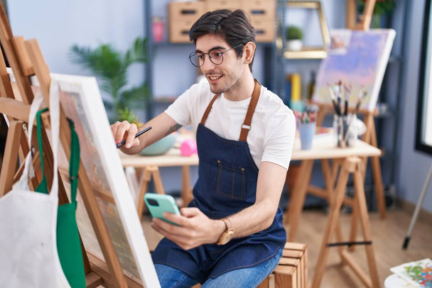 Jovem artista hispânico usando o desenho do smartphone no estúdio de arte - Foto, Imagem