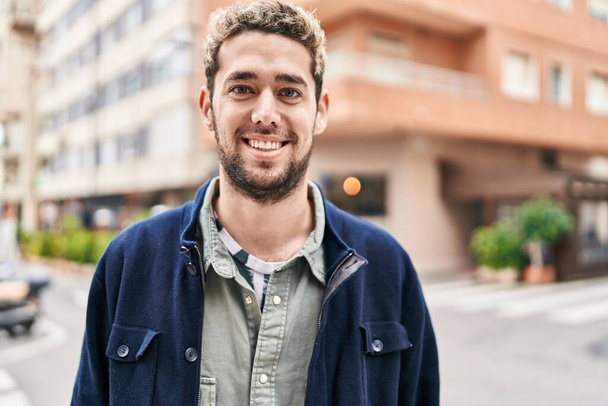 Mladý muž s úsměvem stojí na ulici - Fotografie, Obrázek