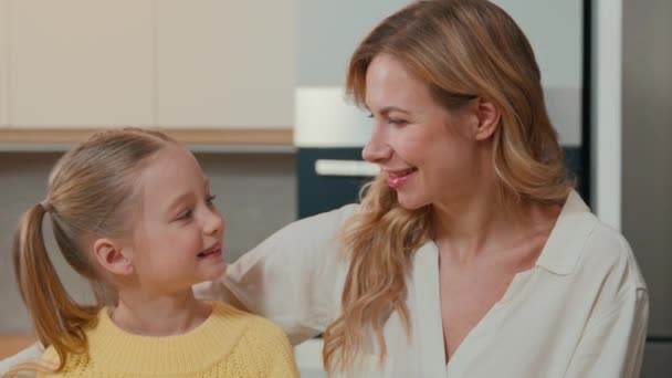 Caucasian happy family at kitchen. Close up smiling child daughter cuddling mom look at camera. Adult single mother foster parent and adopted cute kid girl hug cuddle enjoy sweet tender love portrait - Video
